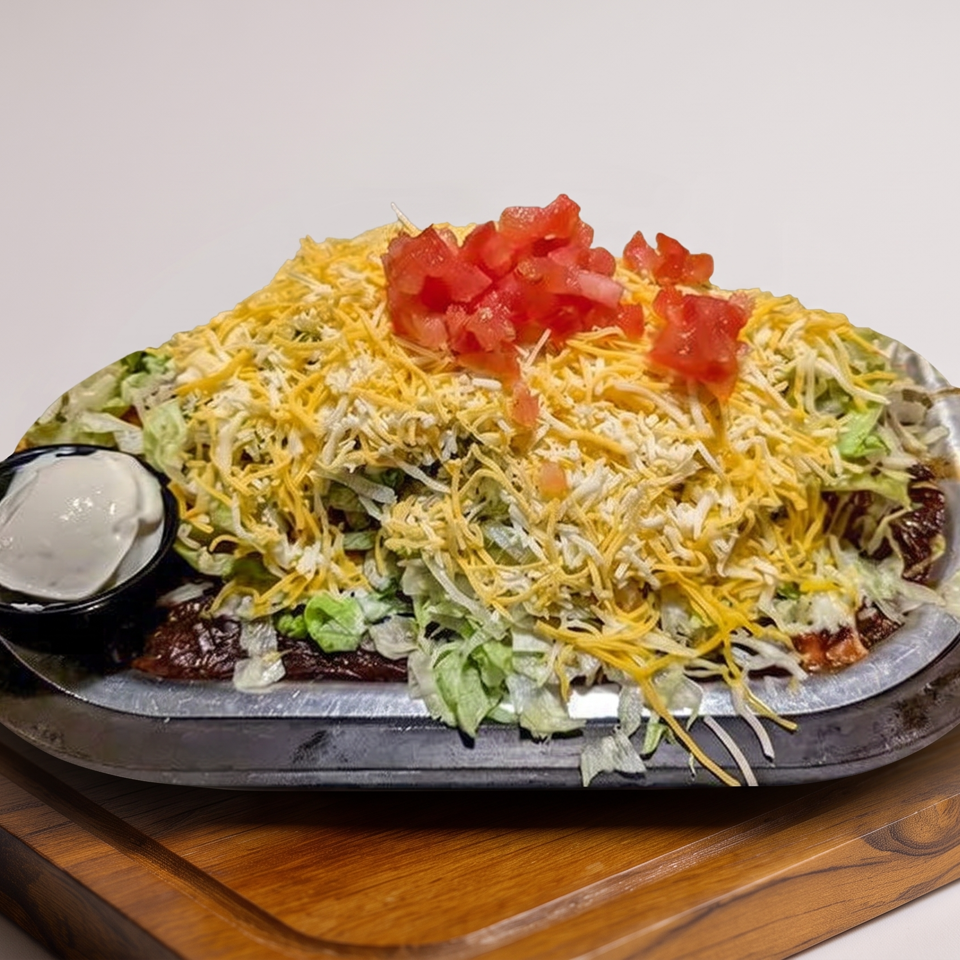 Loaded nachos topped with shredded cheese, lettuce, diced tomatoes, and sour cream on a black platter.